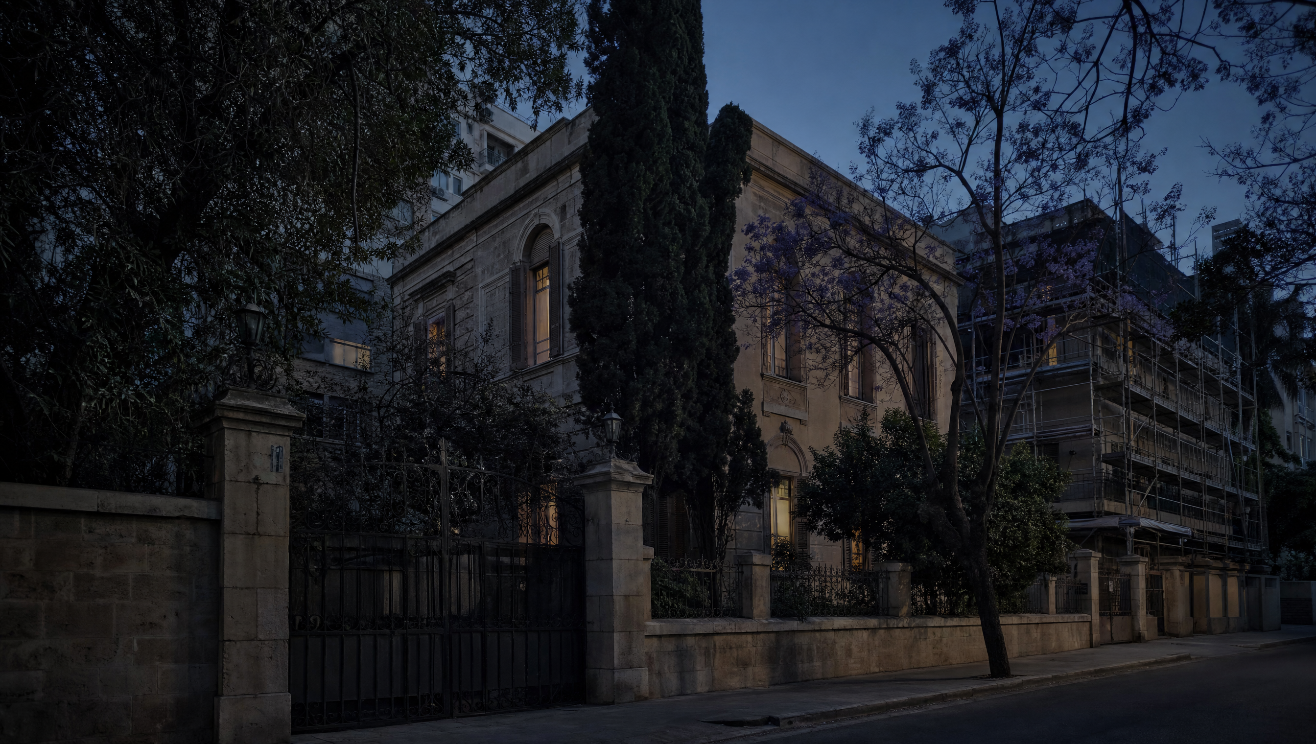 A stone townhouse behind an iron gate on a quiet Achrafieh street at dusk