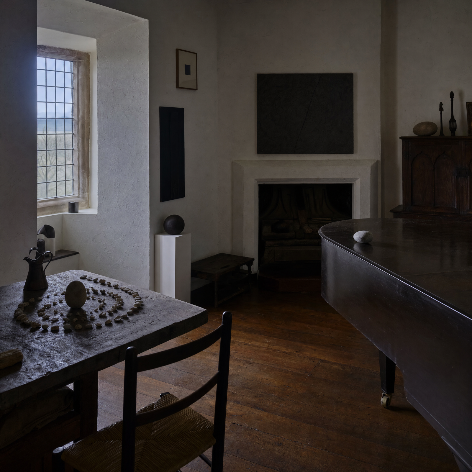 A whitewashed collector's house interior at dusk, low furniture and small objects set out with great care