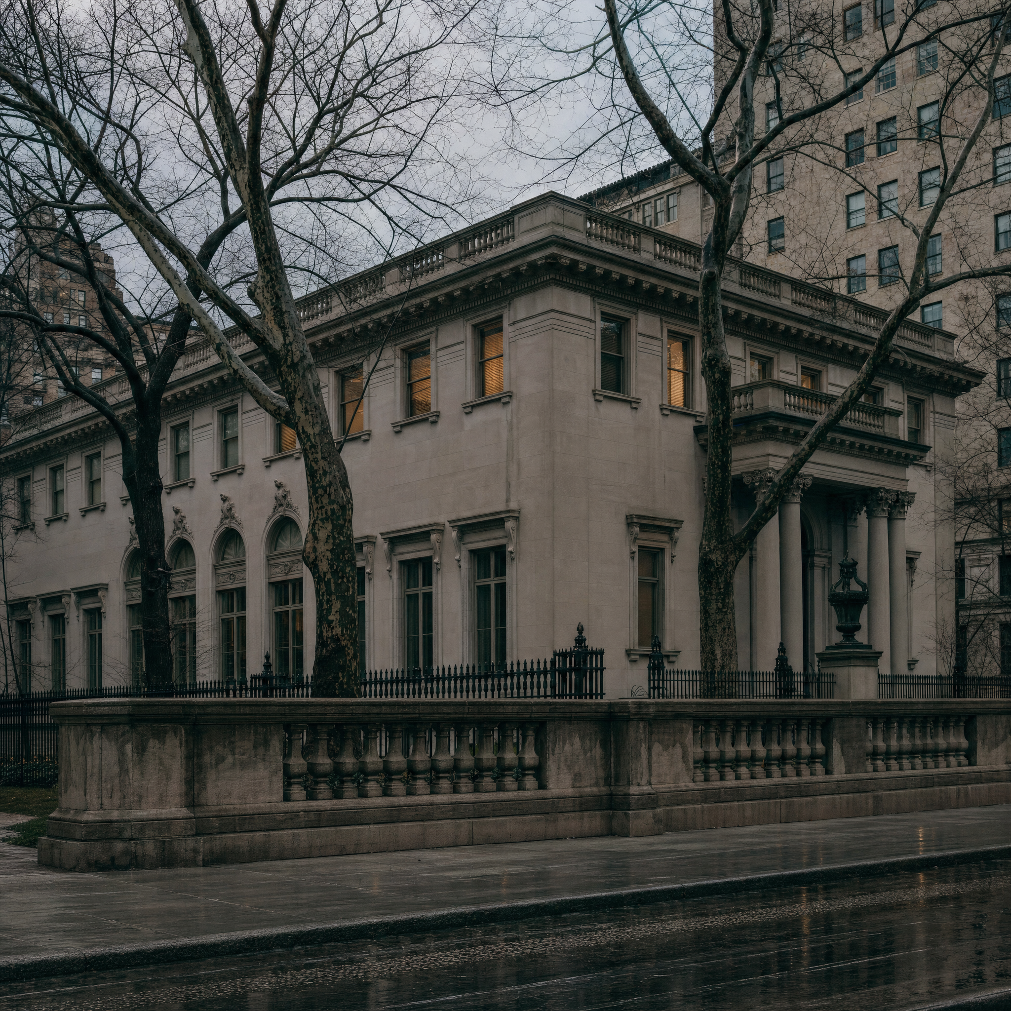 The limestone Fifth Avenue front of the Frick Collection behind its balustrade on a bare winter evening