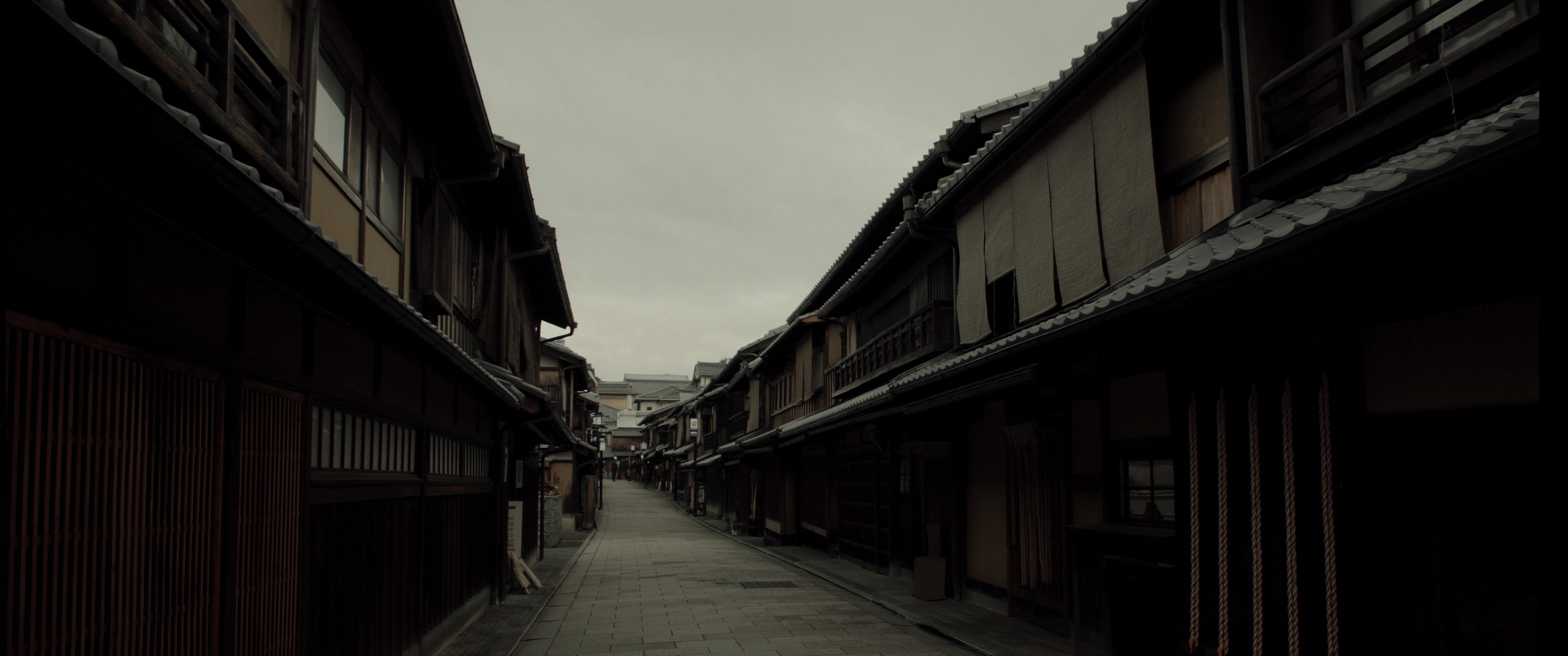 A narrow machiya street in winter, timber lattice and tiled roofs