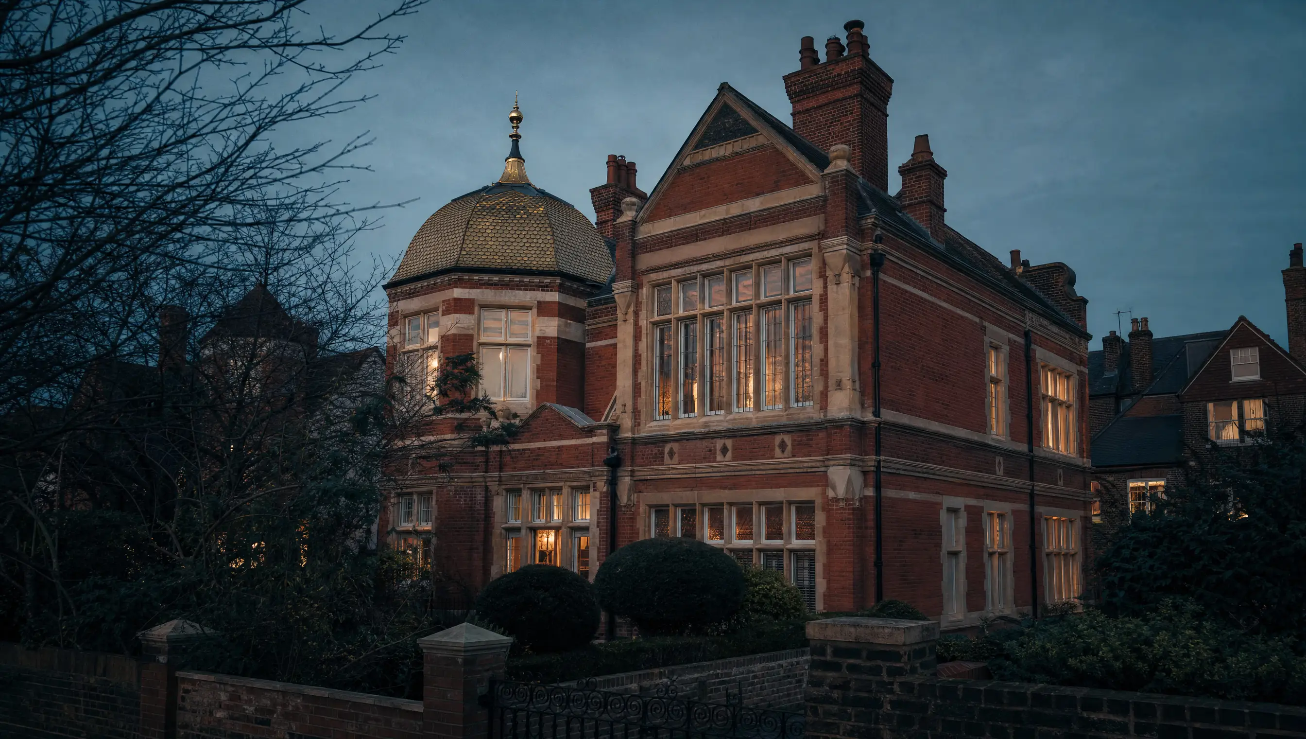 The red brick facade of Leighton House at dusk, the studio window above and the tiled dome beyond