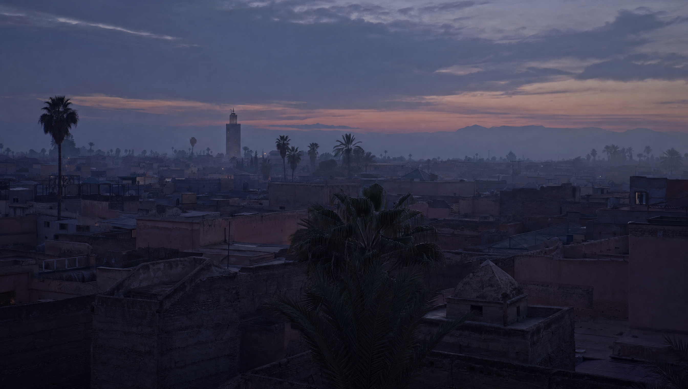 Marrakech rooftops and the old medina at dusk, clay walls gone grey-violet in low February light