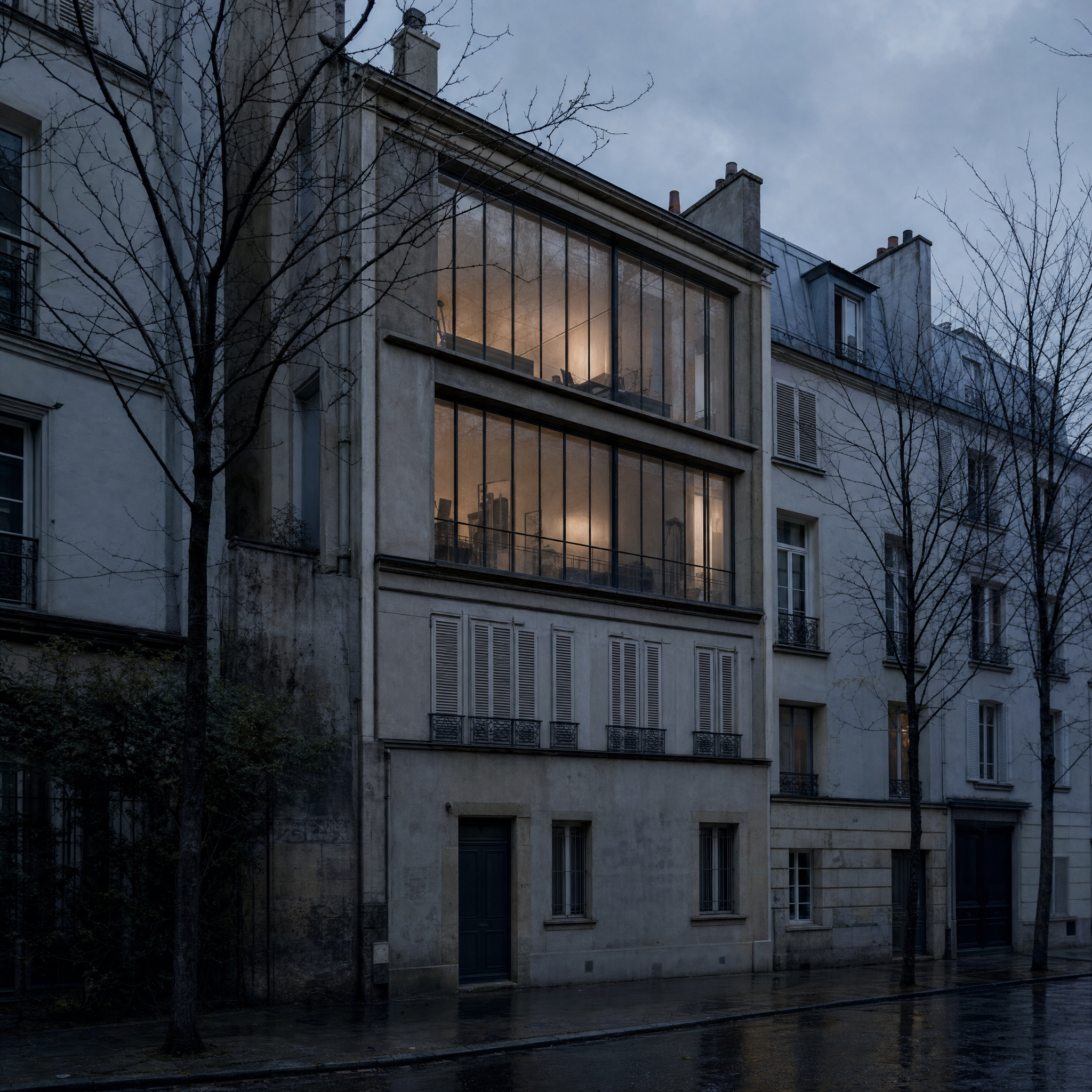 The narrow street front of the Musée Gustave Moreau in the rain, the tall studio glazing lit above