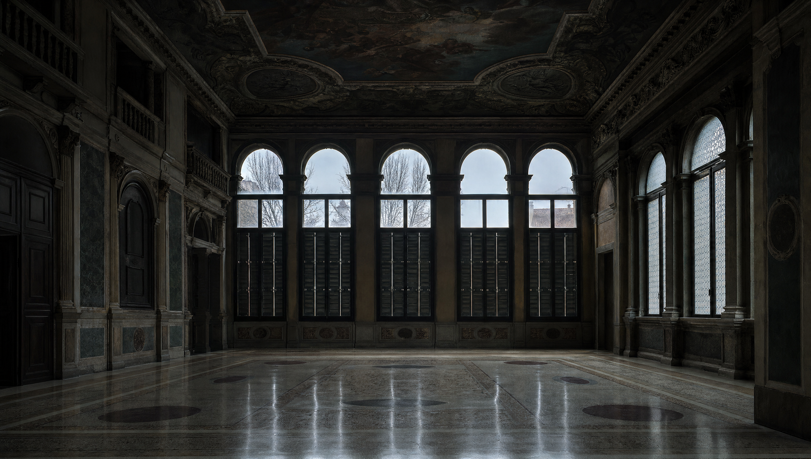 An empty Venetian palazzo hall with a painted ceiling, pale terrazzo floor and tall shuttered windows